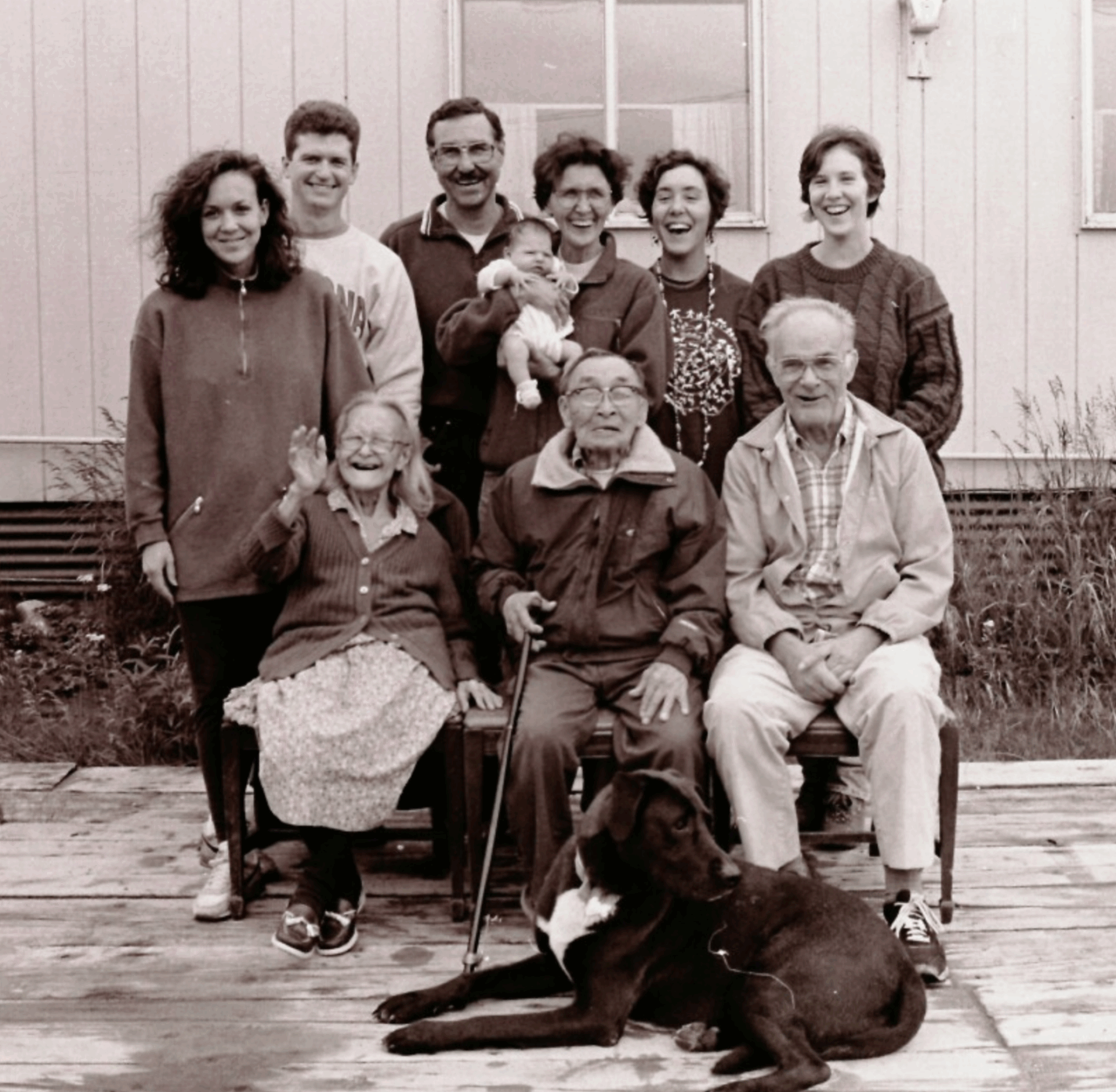 Melanie Brown stands with several generations of her family along with their family dog in this joyful black and white photo.